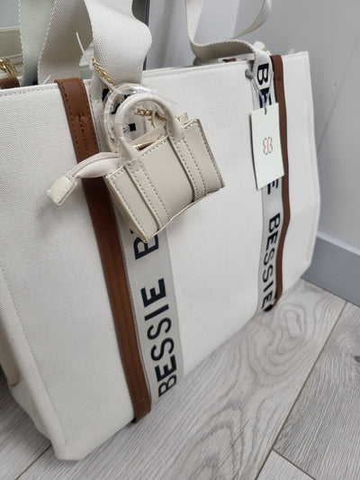 White handbag with brown accents and 'Bessie' branding on a light wooden surface.