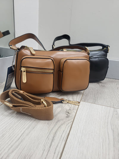 Brown leather bag with a strap on a light wooden surface