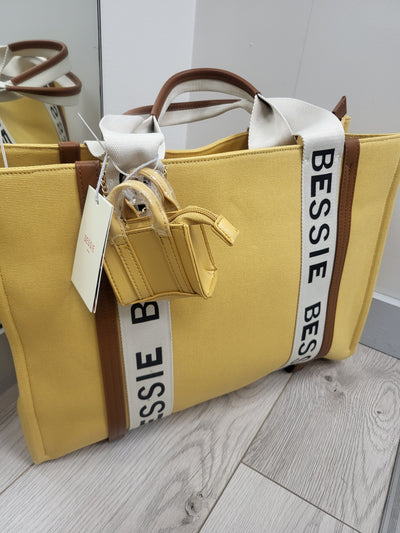 Yellow bag with 'BESSIE' branding on a light wooden floor.