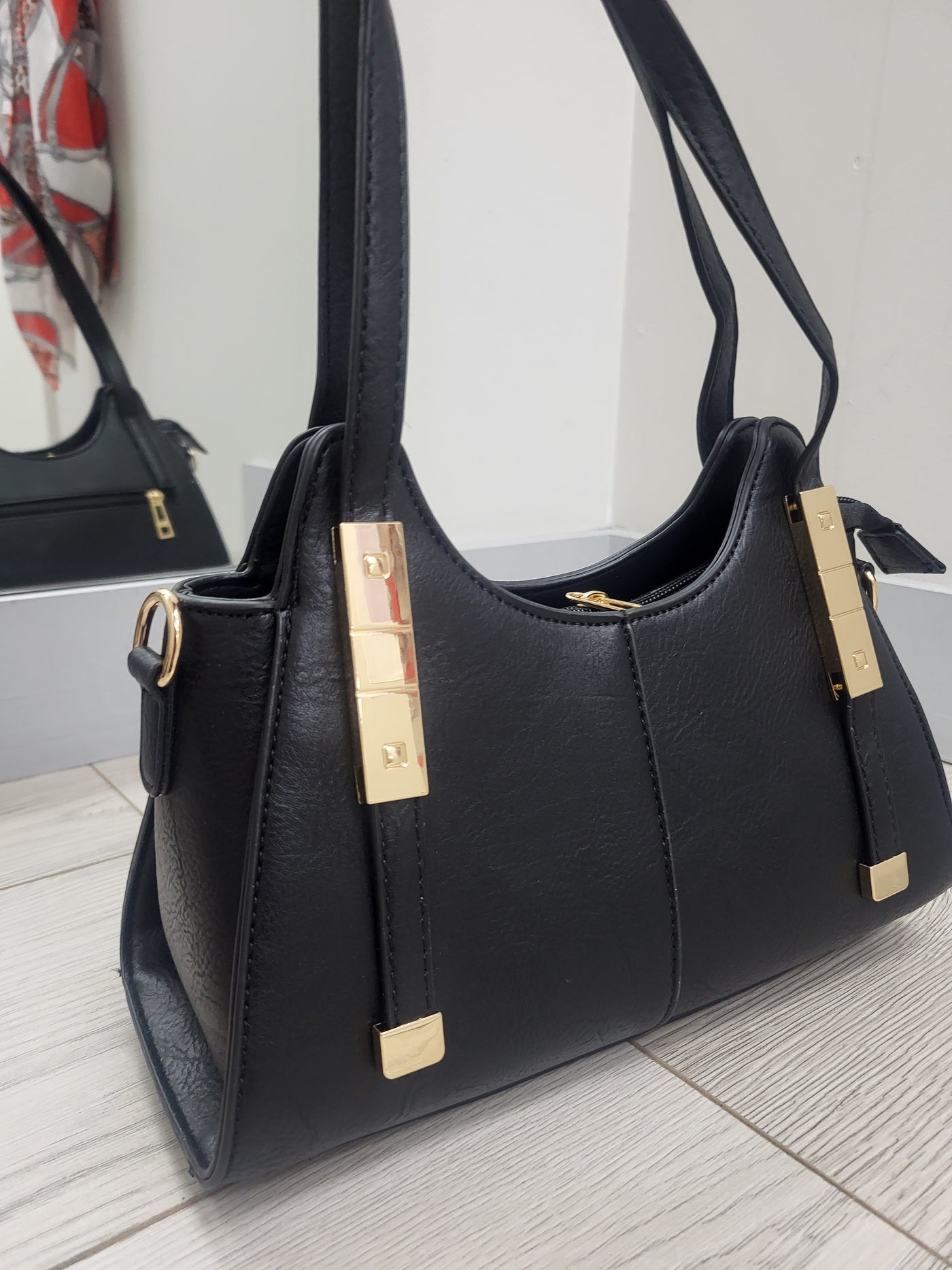 Black handbag with gold hardware on a light wooden floor