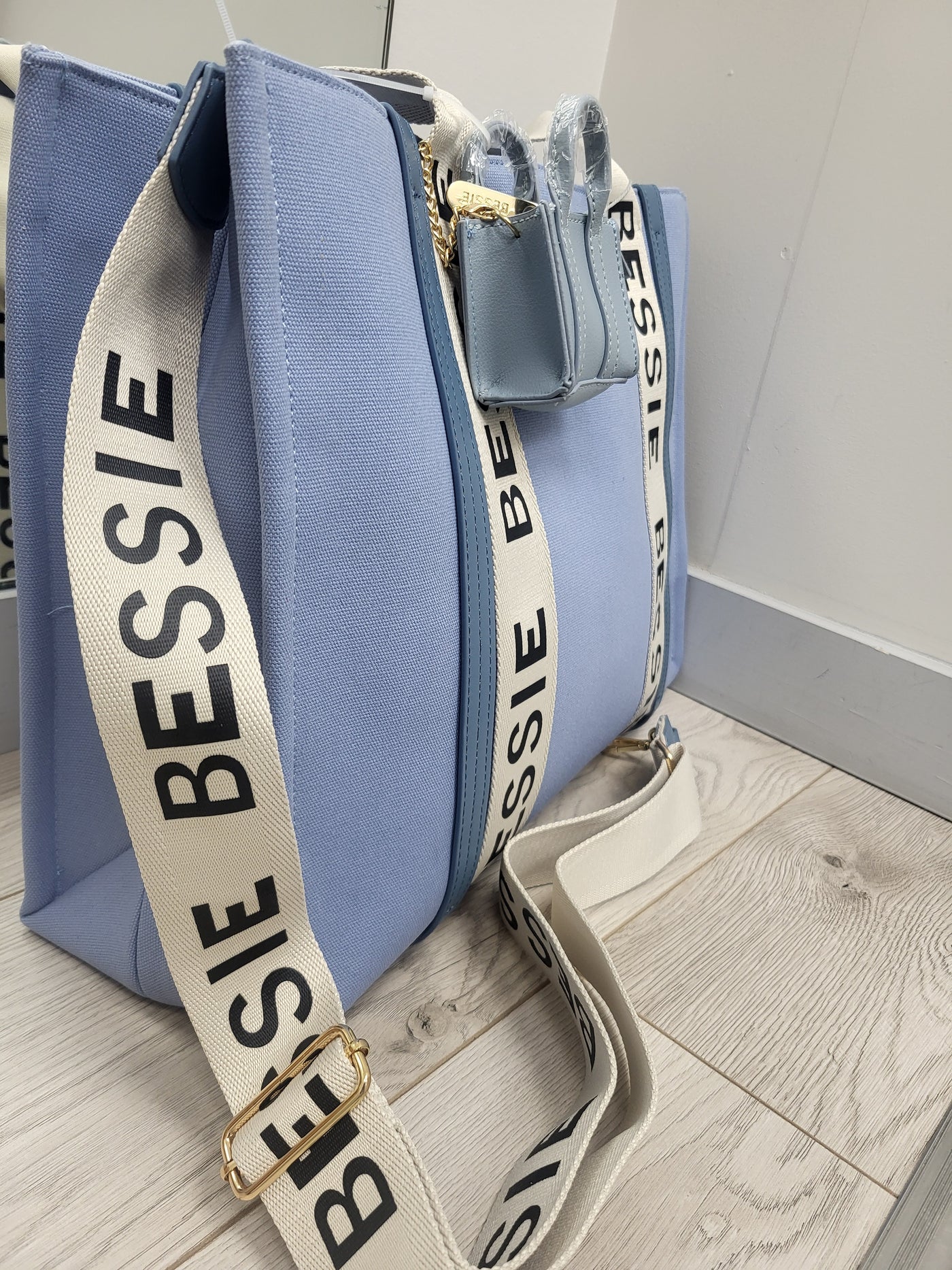 Blue bag with a visible brand strap on a light wooden floor.