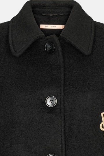 Black coat with buttons and a brand tag on a light gray background