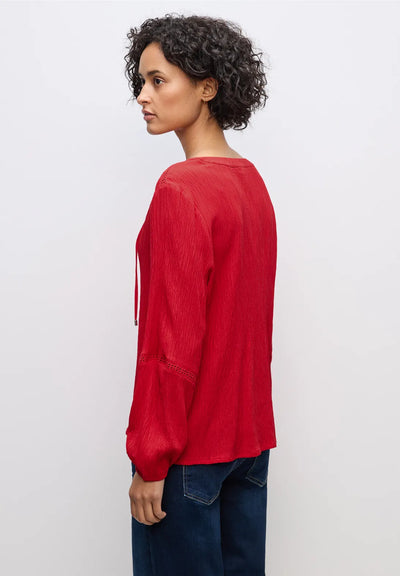 Woman wearing a red long-sleeve top against a white background