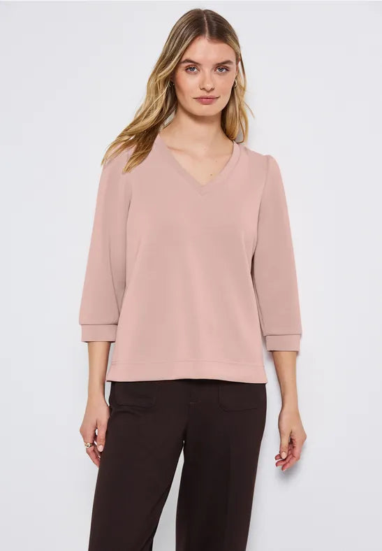 Woman wearing a light pink blouse and black pants on a white background