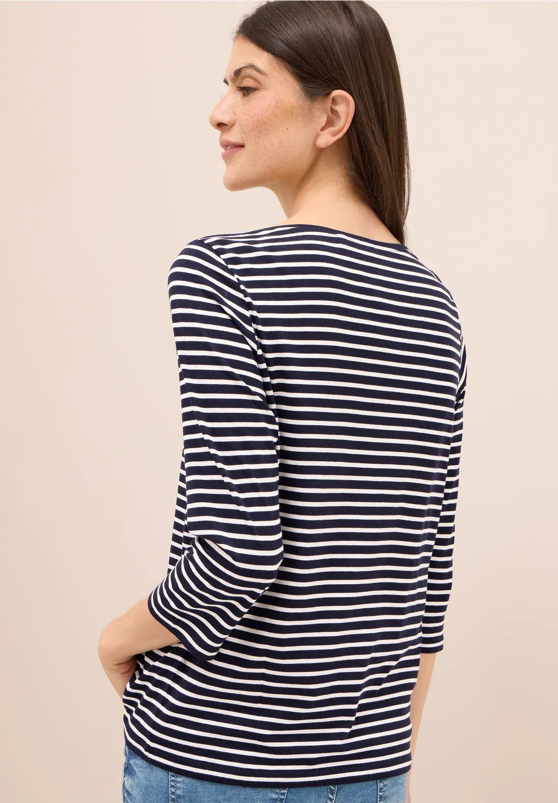 Woman wearing a navy and white striped long-sleeve shirt against a beige background