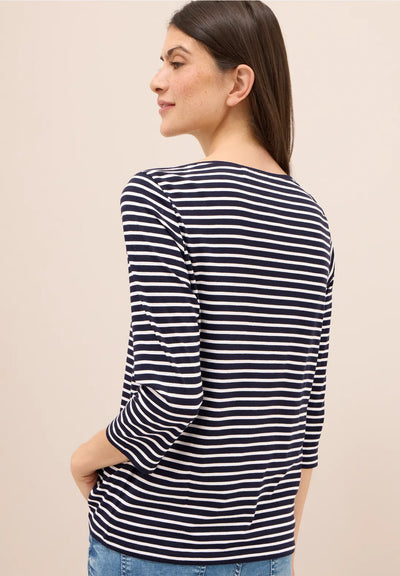 Woman wearing a navy and white striped long-sleeve shirt against a beige background