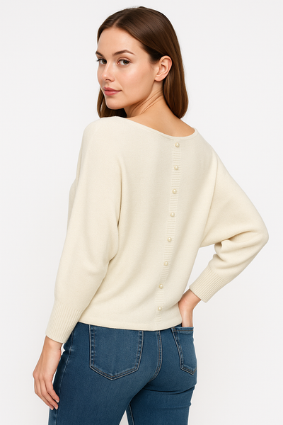 Woman wearing a cream sweater and blue jeans on a white background